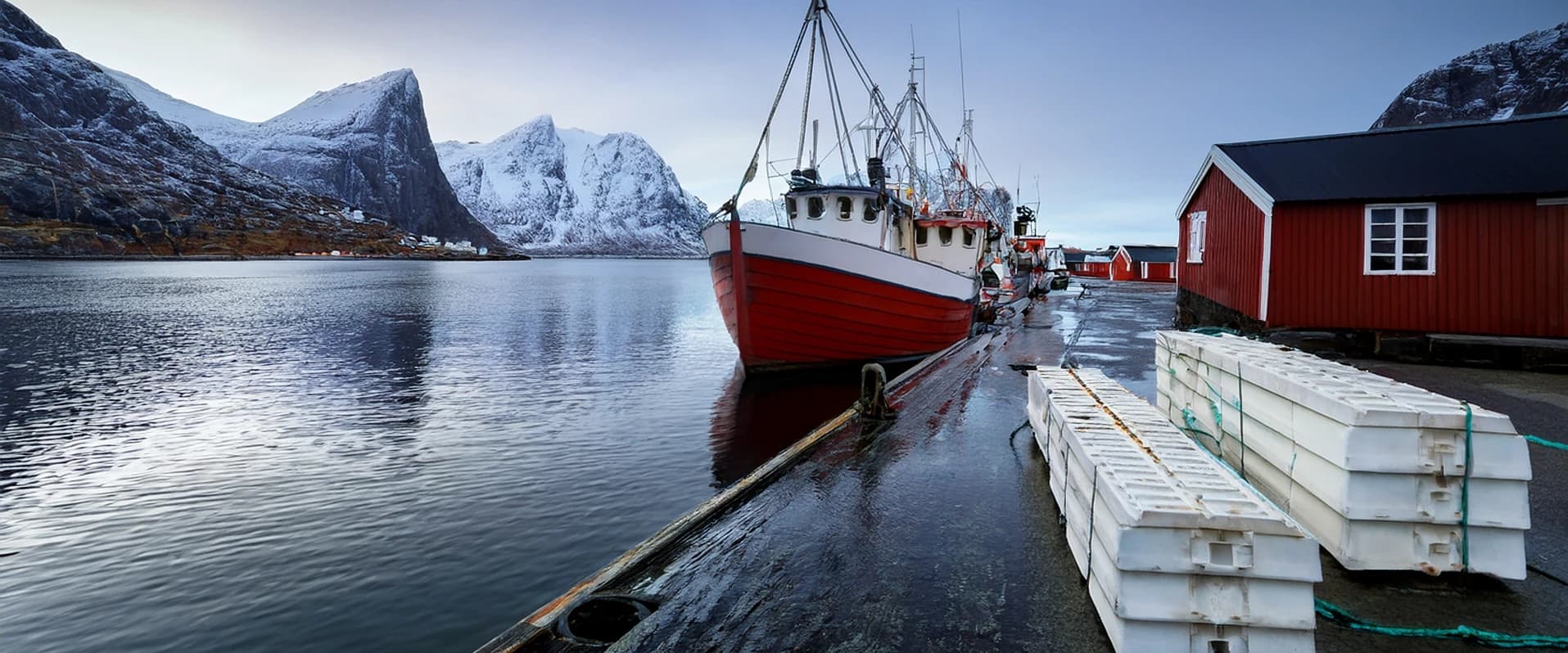 A Norwegian fishing harbour at first light, a vessel alongside the quay and polystyrene fish boxes stacked on it