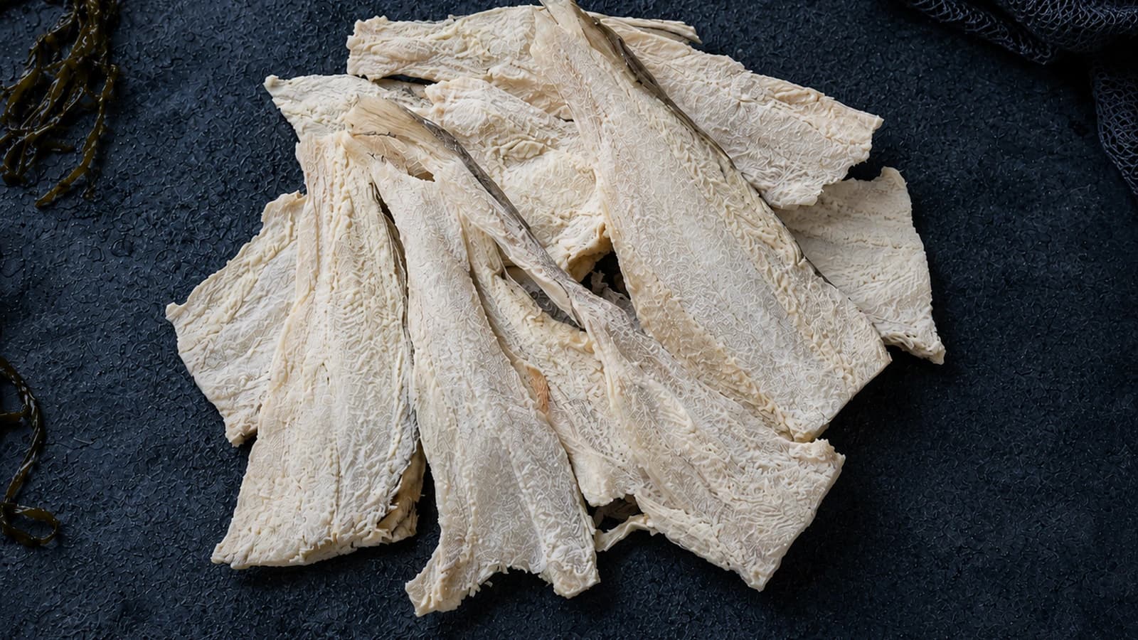 Pale salted and dried klippfisk pieces on dark slate